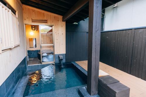 a room with a pool of water in a house at Tawarayama Onsen Ryokan Minawa in Minami Aso