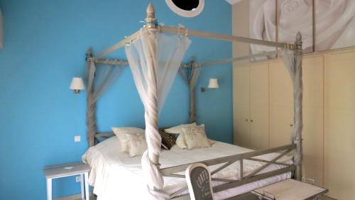 a bedroom with a canopy bed with blue walls at Le Mas du Lingousto in Cuers