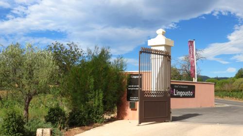 a sign in front of a building with a gate at Le Mas du Lingousto in Cuers