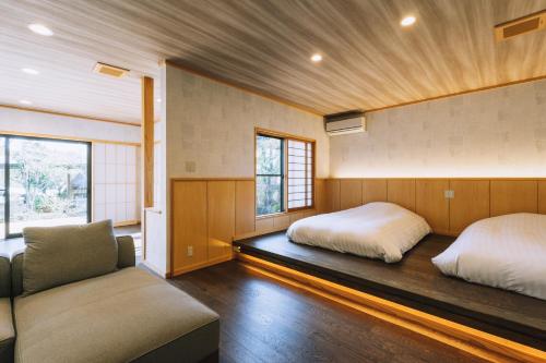 a bedroom with two beds and a couch at Tawarayama Onsen Ryokan Minawa in Minami Aso