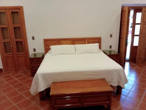 Schlafzimmer mit einem weißen Bett und Holzmöbeln in der Unterkunft Casa Purépecha, Habitación Itzi in Morelia