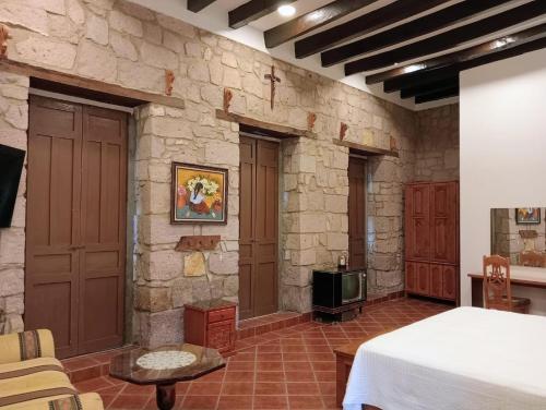 Zimmer mit einer Steinmauer, einem Bett und einem TV in der Unterkunft Casa Purépecha, Habitación Itzi in Morelia