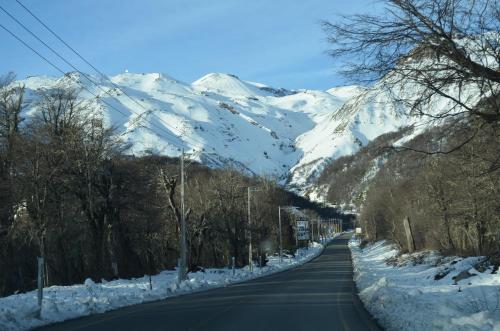 an empty road with snow covered mountains in the background at Departamento Termas de Chillan in Nevados de Chillan