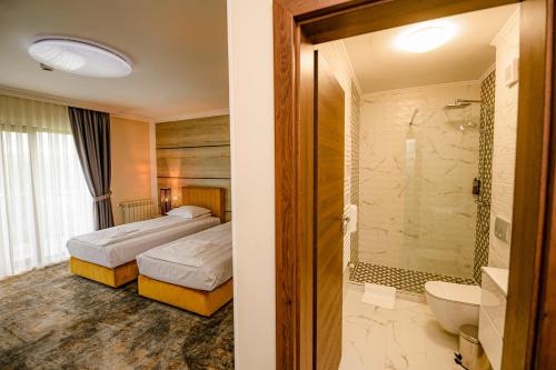 a hotel room with two beds and a shower at Allegria Hotel in Alba Iulia
