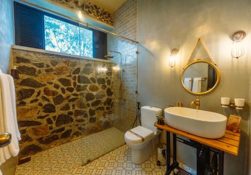 a bathroom with a sink and a toilet and a mirror at Rosewood Manor in Botiyatenna