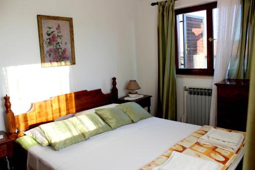 sypialnia z dużym białym łóżkiem i oknem w obiekcie Apartments Cavae Romanae w Medulinie
