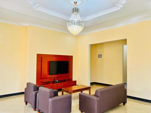 een woonkamer met stoelen en een televisie en een kroonluchter bij CnRAirBnB in Iringa