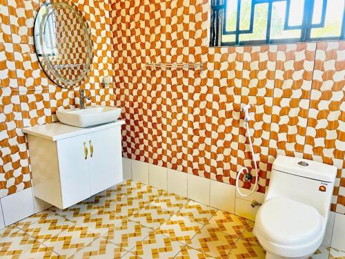 een badkamer met een toilet, een wastafel en een spiegel bij CnRAirBnB in Iringa
