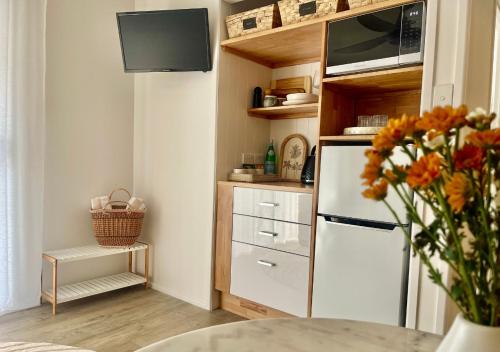 a kitchen with a refrigerator and a vase of flowers at Jasmine Hideaway Guesthouse Near SCUH Hospital in Kawana Waters