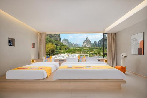 a bedroom with two beds and a large window at Yangshuo Yundu Panoramic Luxury Hotel in Xingping