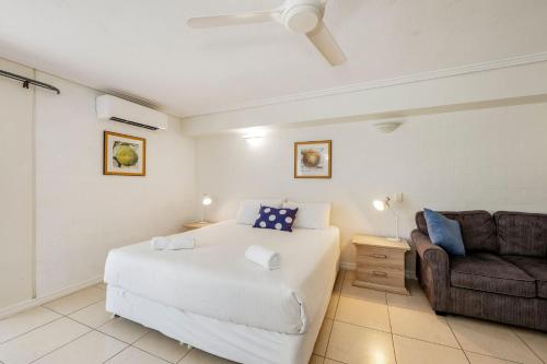 a bedroom with a white bed and a couch at Shoreline Apartments - Unit 4a in Bargara