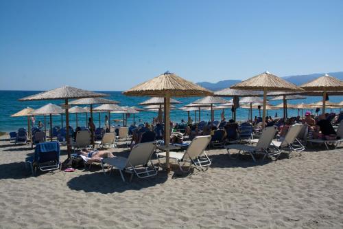a group of people sitting in chairs under umbrellas on a beach at Land of Gods in Gythio
