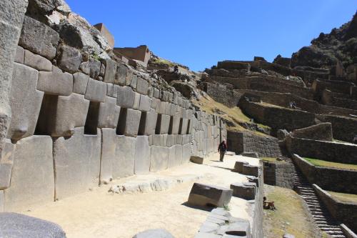 a person standing in front of a stone wall at Hotel Tierra Inka Sacred Valley in Ollantaytambo