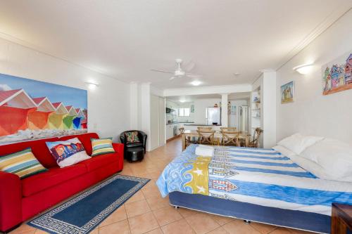 a bedroom with a bed and a red couch at Shoreline Apartments - Unit 9a in Bargara