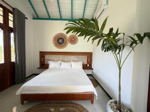 een slaapkamer met een bed en een potplant bij ISOLA - Surf House in Koggala