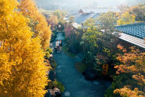 two people walking down a path in a garden at 四季の宿 明翠 in Kirishima