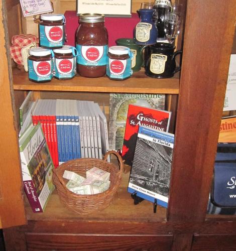 a book shelf filled with jars and a basket of books at St. Francis Inn - Saint Augustine in Saint Augustine