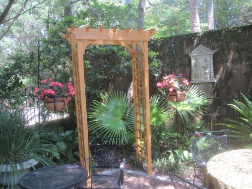 a wooden arch in a garden with potted plants at St. Francis Inn - Saint Augustine in Saint Augustine