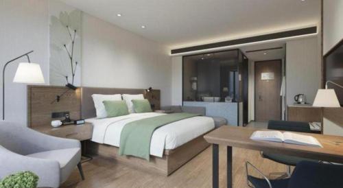 a bedroom with a large bed and a desk and a room with a deskablish at GreenTree Inn Express Hainan Haikou Haixiu Zhong Road in Haikou