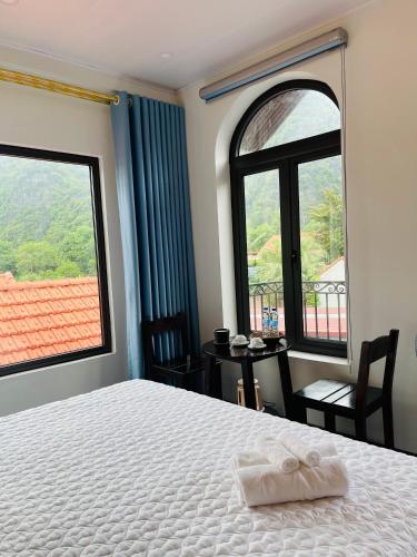 a bedroom with a bed and two large windows at Tam Coc Hope House in Ninh Binh