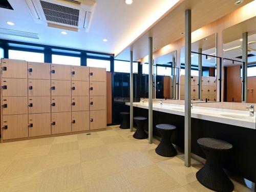 Un vestuario con taquillas, lavabos y espejos. en APA Hotel Oita Ekimae, en Oita