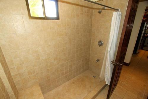 y baño con ducha y puerta de cristal. en Sunset Heights 402, en Playa Flamingo