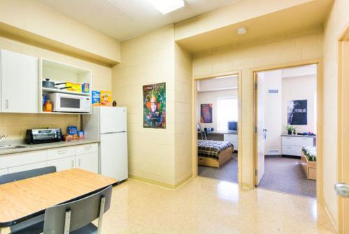 eine Küche mit einem Kühlschrank und ein Zimmer mit einem Bett in der Unterkunft Residence & Conference Centre - Sudbury North in Sudbury