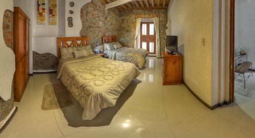 a bedroom with two beds and a television in it at Alqueria de Carrion Hotel Boutique in Atlixco