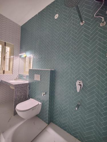 a bathroom with a toilet and a green tiled wall at Virudravilla in Jodhpur