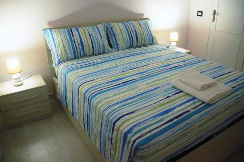 a bed with a striped bedspread and two lamps at Hello Roma B&B in Rome