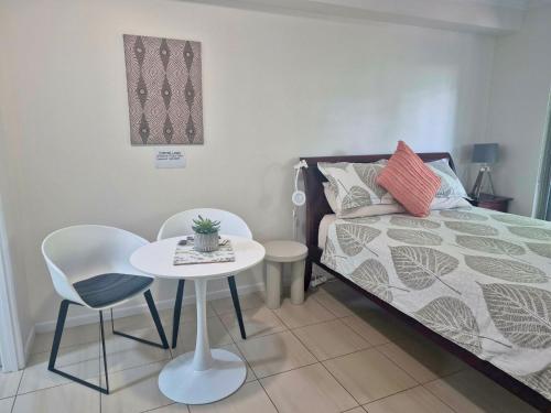 a small room with a bed and a table and chair at Studio close to Airport, City & Esplanade in Cairns North