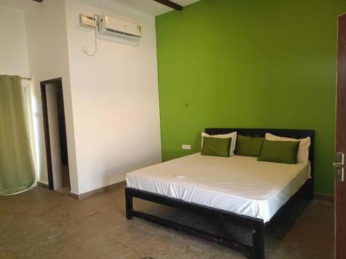 a bed in a room with a green wall at REWOGA Gaia Resort - Luxury Rooms with Open-Air Shower in Arambol