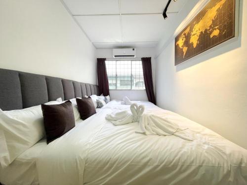 #SE Cozy&Warm 3Bedroom HomeStay 10PAX by S&T Homez في سِريمبان: سرير ابيض كبير عليه منشفتين بيضاء