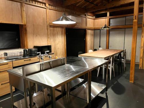 ŌwadaにあるHostel Inn かすみがうら 仁左ェ門のシンクとテーブルと椅子のあるキッチン