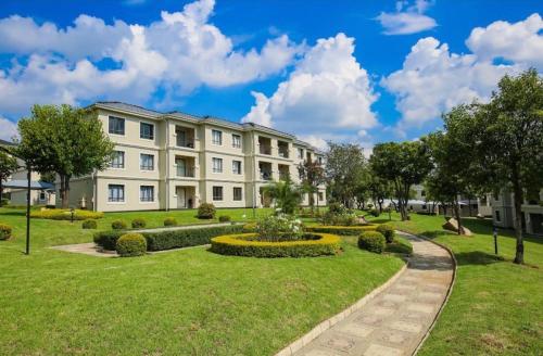 Cedar Square Apartment في Trevallyn: مبنى أبيض كبير مع حديقة أمامه