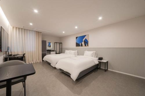 a bedroom with a large white bed and a desk at Cheongju The City Hotel in Cheongju