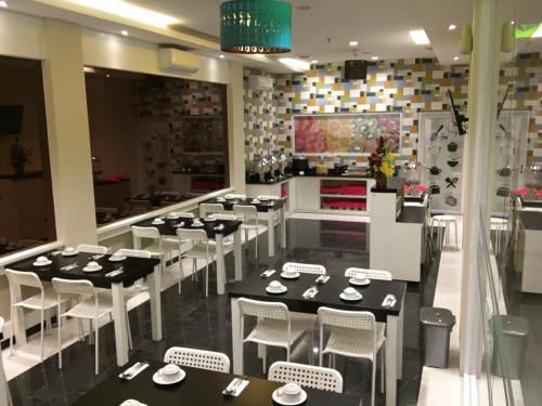 a dining room with black tables and white chairs at MSquare Palembang in Palembang