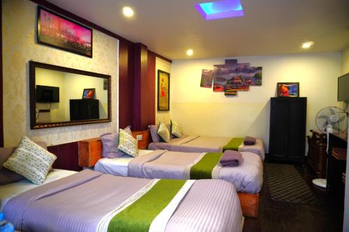 a hotel room with three beds and a mirror at Hotel Shree Tara in Kathmandu