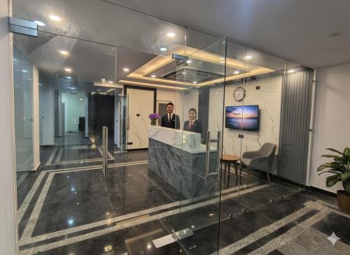 Dos personas de pie en un mostrador en un vestíbulo. en Expo Residency Inn, en Jāmb