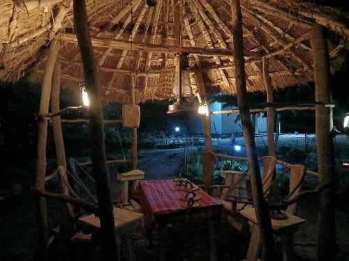 a tent with a table and chairs under a straw umbrella at Makucha Ya Simba Homestay and camping grounds in mwanza 