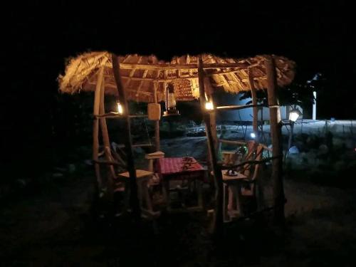 a hut with a table and chairs at night at Makucha Ya Simba Homestay and camping grounds in mwanza 