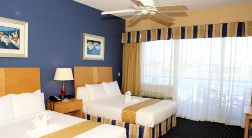 a hotel room with two beds and a ceiling fan at Chart House Suites and Marina in Clearwater Beach