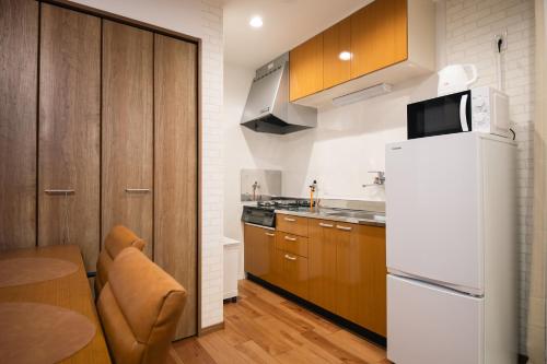 a kitchen with a white refrigerator and wooden cabinets at Private House KANADE in Nara