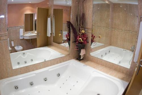 a large bathroom with a large tub and a large mirror at Hotel los Girasoles in Valencina de la Concepción
