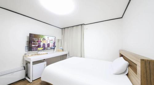 a white bedroom with a bed and a desk at The Oakra Hotel in Jeju