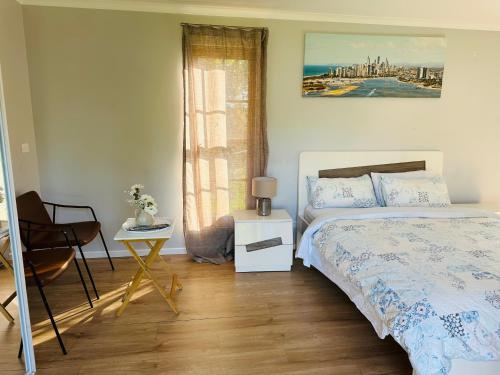 een slaapkamer met een bed, een stoel en een raam bij Modern Rustic Backyard Studio Private & Cosy Retreat in Mount Tamborine