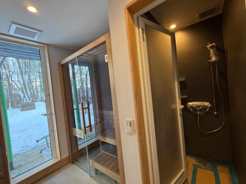 a bathroom with a shower and a glass door at The Guest House Japan Hakuba in Hakuba