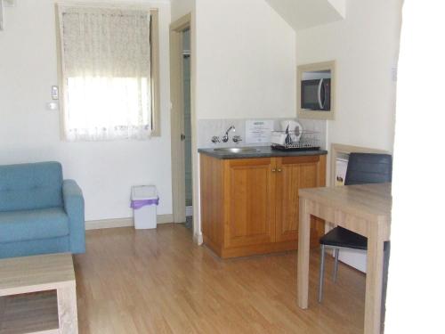 a small kitchen with a table and a blue couch at Queechy Motel in St Helens