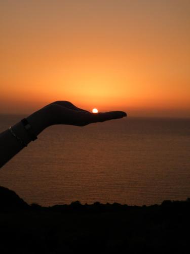 a sunset over the ocean with a persons silhouette at Charly Point Villa in Methoni
