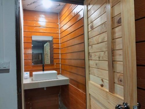 a bathroom with wooden walls and a sink and a mirror at Koh jum Mutu Home Stay in Ban Ko Phrao